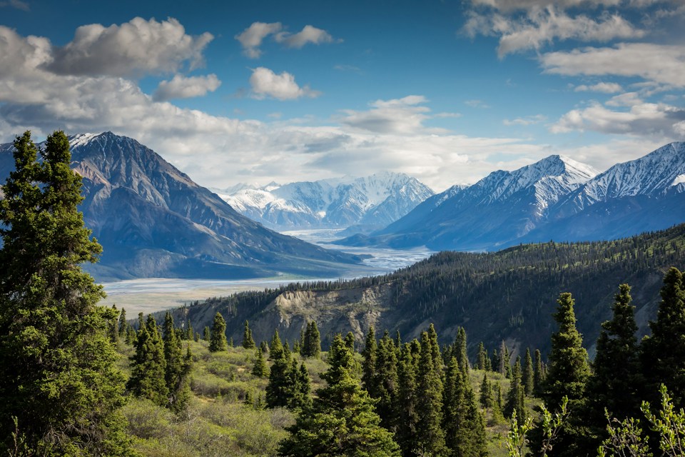 A sunlit mountain valley beneath a wide blue sky