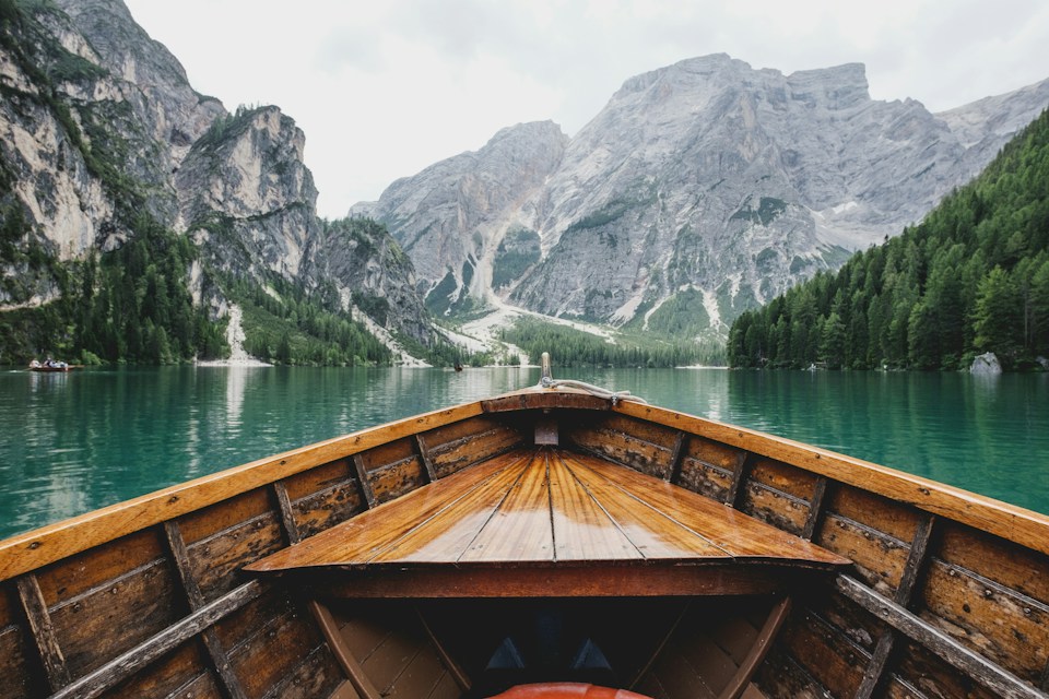 A wooden boat on a turquoise lake surrounded by mountains